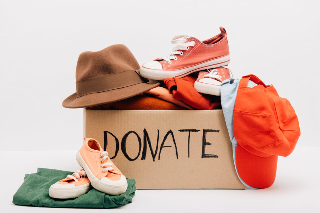 cardboard box with donated accessories, clothes and footwear isolated on white, charity concept