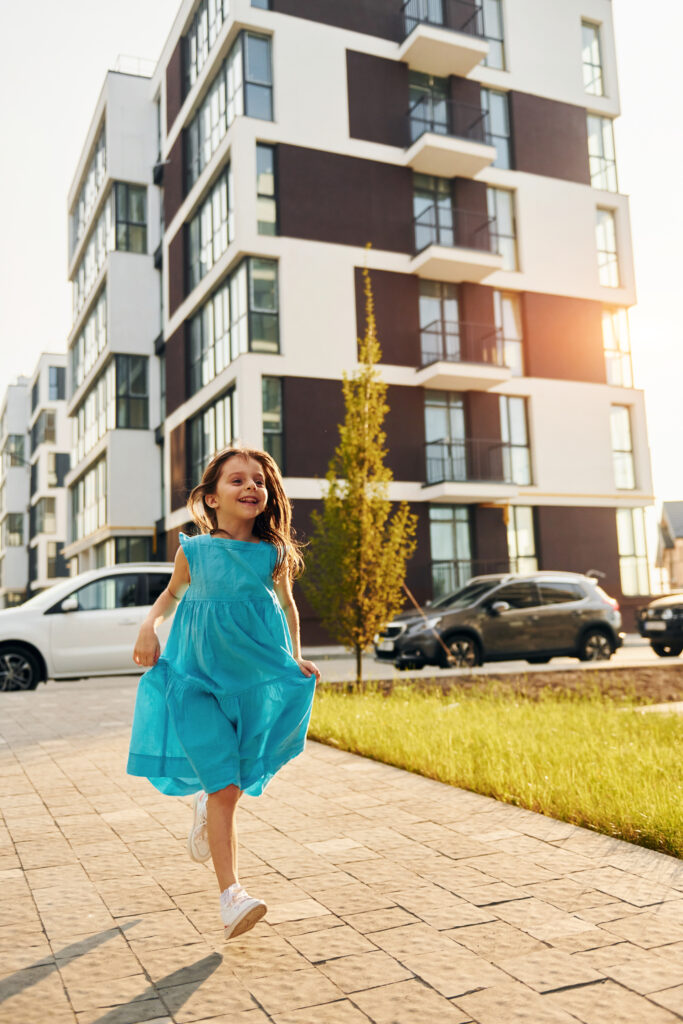 Cheerful little girl walking outdoors in the city in dress
