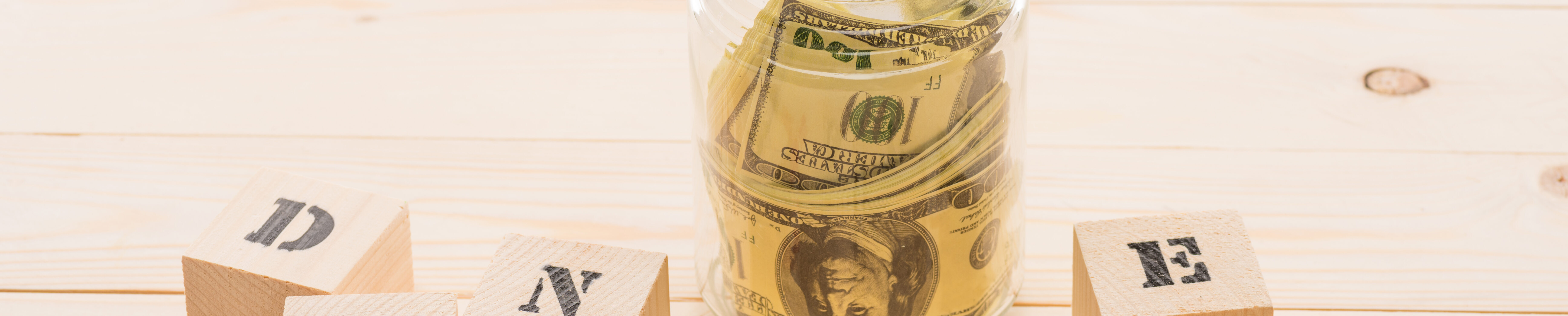 Dollar banknotes in glass jar and wooden cubes with donate lettering, donation concept